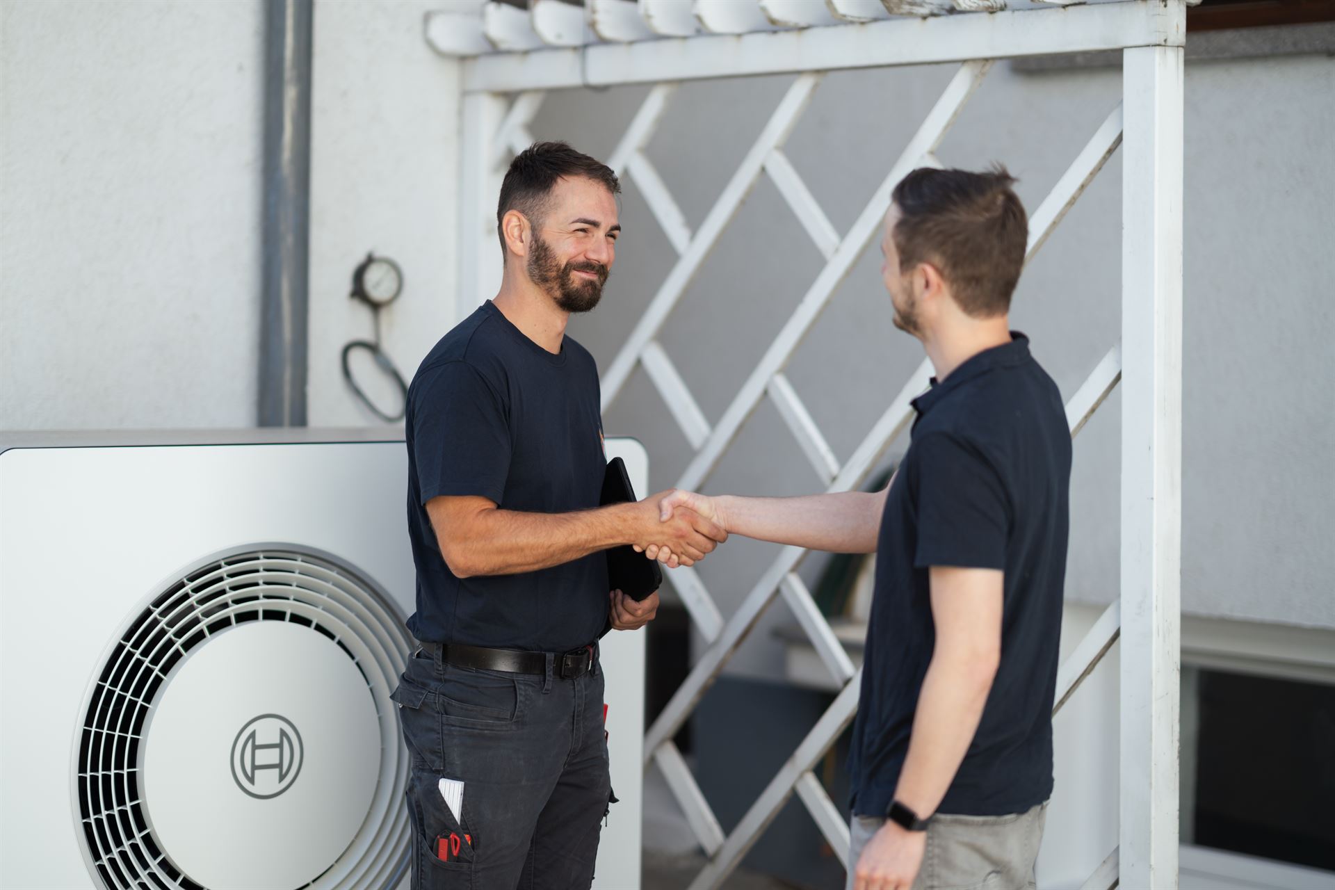 Techniker und Kunde geben sich nach der Übergabe der Wärmepumpe die Hand